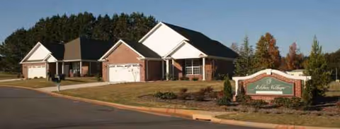Exterior view of Ashlan Village senior living facility with brick front and welcoming sign.