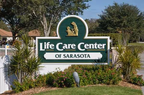 Front sign for Life Care Center of Sarasota with landscaping and trees