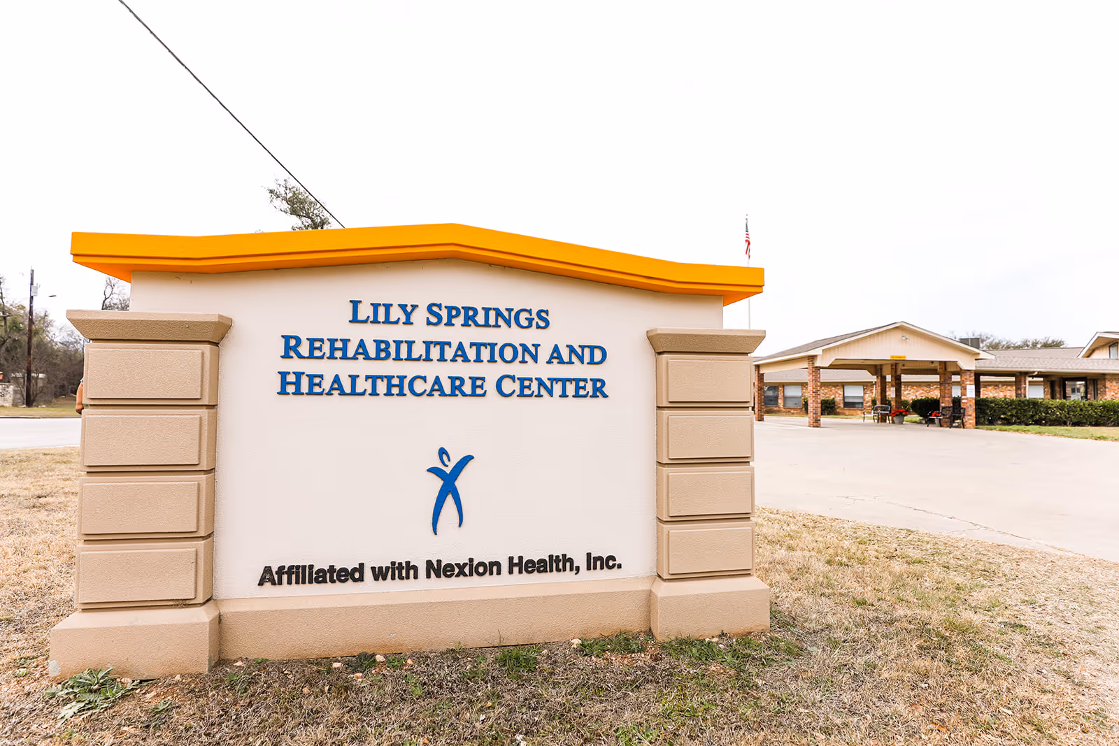 Entrance sign reading "Lily Springs Rehabilitation and Healthcare Center" in front of the facility building and drive-up entrance.