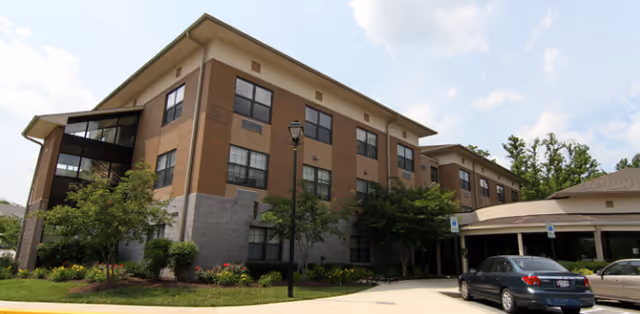 Tiber Hudson senior living facility exterior with brick facade, landscaping, and a parking area.