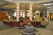 Spacious lobby with decorative columns, a small fountain, bench, and seating area.