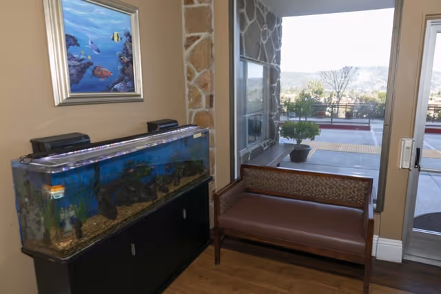 Lobby area with a large aquarium, a bench and a glass entry door opening to an exterior patio.