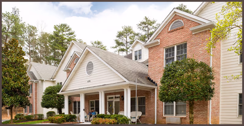 Exterior view of Country Gardens Dunwoody entrance with porch seating and surrounding trees