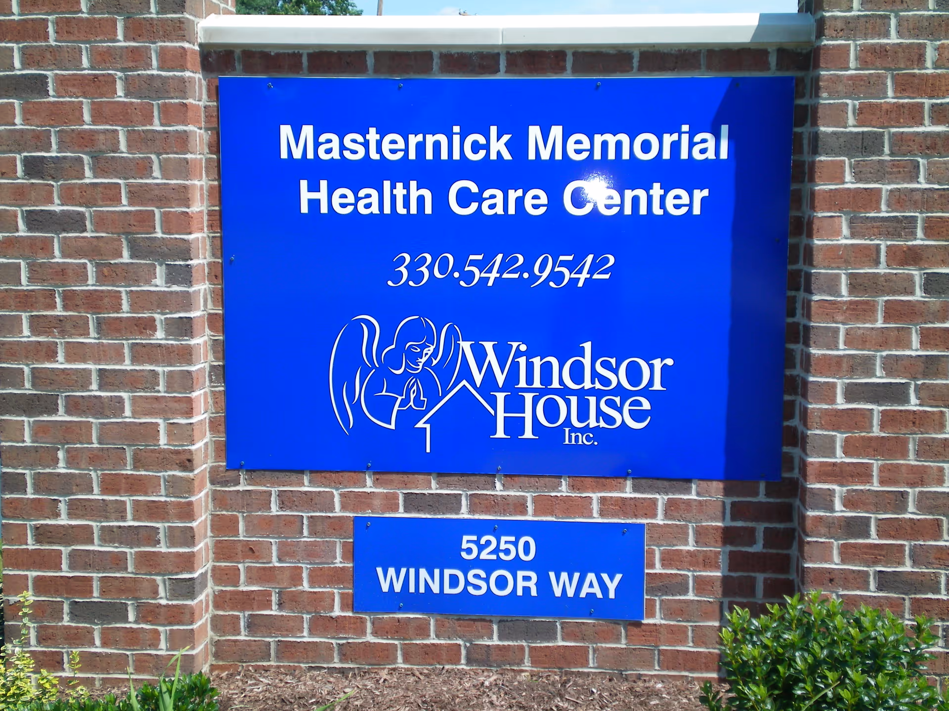 Blue sign on a brick wall reading 'Masternick Memorial Health Care Center' and 'Windsor House' with address '5250 Windsor Way'.
