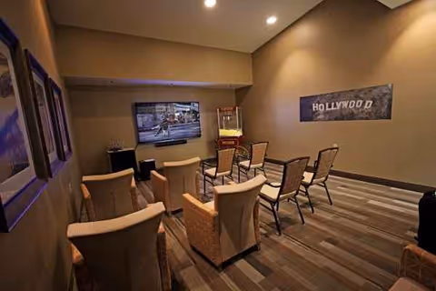 Interior lounge with chairs facing a TV and Hollywood sign décor.