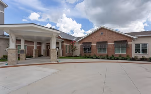 Exterior view of Delaney at South Shore, a brick senior living facility with a covered entrance.