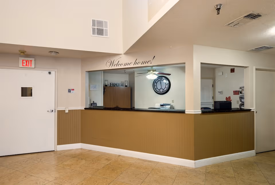 Reception area with a front desk, a "Welcome home!" sign above the counter, a wall clock, and an exit door.