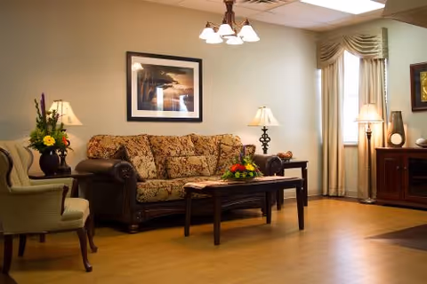 Cozy living room with a floral-upholstered sofa, armchairs, coffee table, lamps, and framed artwork.