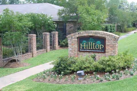 Exterior view of Hilltop Nursing & Rehabilitation Center sign with landscaped entrance.