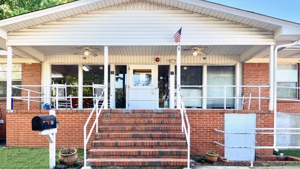 Front entrance of a brick building with steps, wheelchair ramps, a small American flag, and a mailbox.