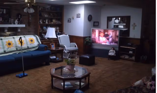 Cozy living room in a senior facility with furniture, shelves, and a TV.
