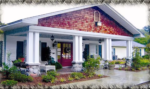Front view of Stoneybrook Memory Care Home with white columns and red doors.