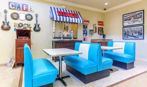 Retro diner-style dining area with turquoise booth seating, tables, and vintage wall decor including guitars and Route 66 signs.