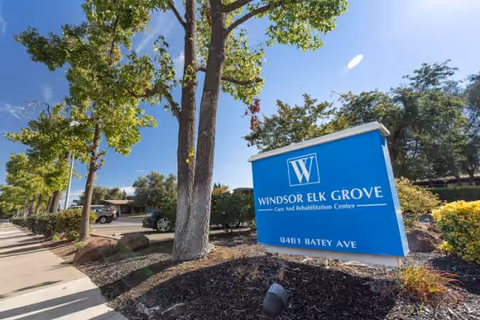 Blue Windsor Elk Grove sign in front of a landscaped facility exterior with trees