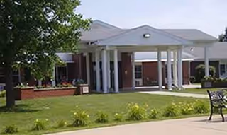 Front view of Monroe Manor's entrance with columns and a manicured lawn.