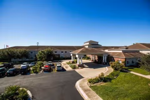 A senior living facility exterior with a covered entrance and parking area.