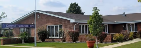 Exterior view of Gilman Healthcare Center, brick building with sign and surrounding landscaping.