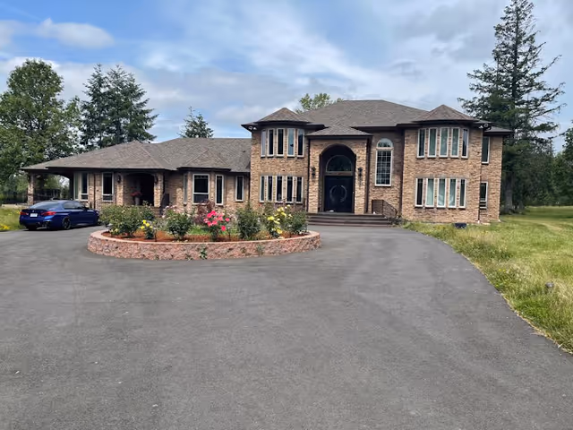 Front view of a brick senior care facility with a circular flower bed and driveway.