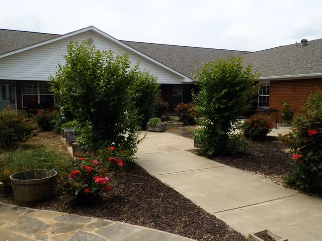 Front exterior view of Clarksville Retirement Center with walkway, landscaping, and shrubbery