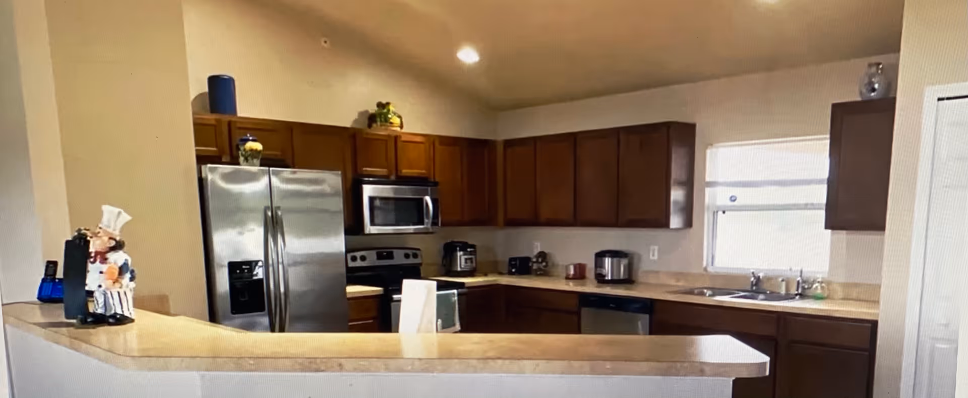 Spacious kitchen with stainless steel appliances, dark wood cabinets, a countertop peninsula, and a sink beneath a window.