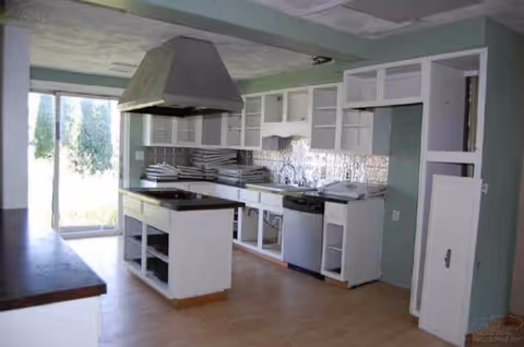 A kitchen in a senior living facility with an island, cabinets, and a large range hood.