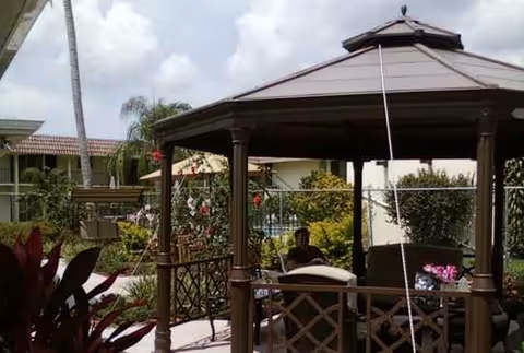 Outdoor gazebo patio with seating and residents enjoying the shaded area.