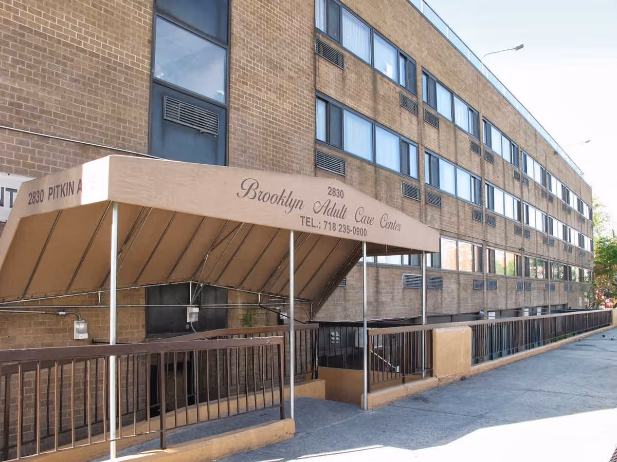Exterior front of a multi-story brick building with a beige awning reading 'Brooklyn Adult Care Center' above the entrance.