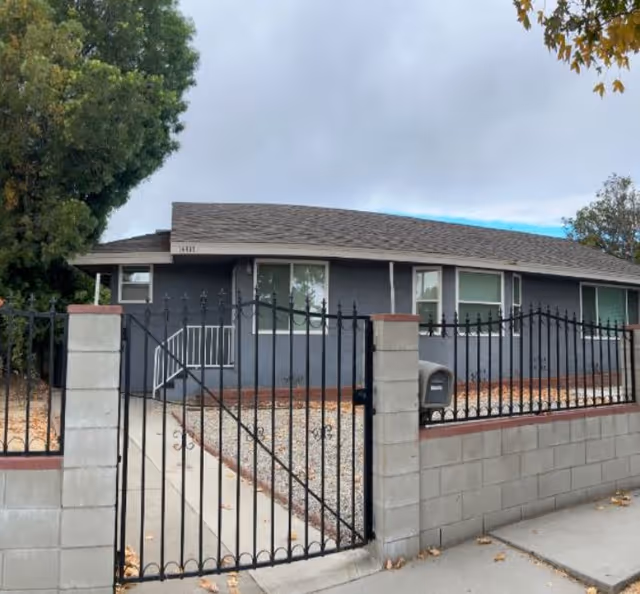 Exterior view of a single-story senior living facility behind a black metal gate