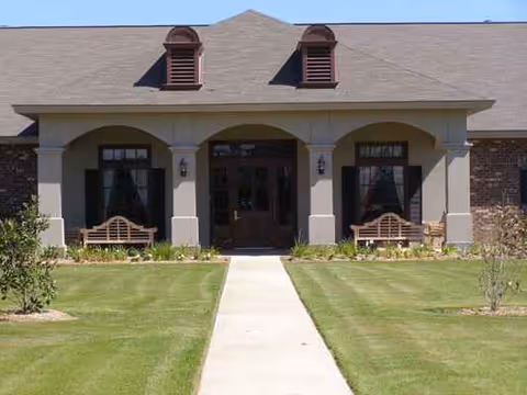 Entrance to Senior Village Nursing & Rehab Center with walkway, lawn, and benches.