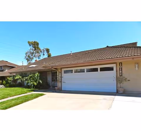 Front view of a single-story home with a white garage door and tiled roof.