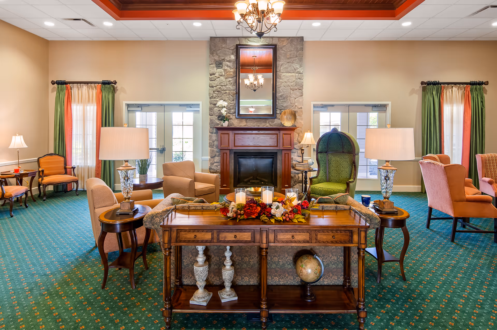 Bright formal sitting room featuring a stone fireplace, multiple upholstered chairs, decorative lamps, and a wooden console table with a floral centerpiece.