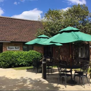 Absecon Manor Nursing Home exterior with patio seating and green umbrellas.