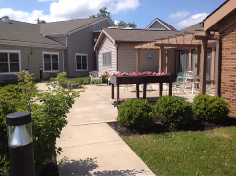 Sunny outdoor courtyard with seating, planters, and adjacent residential-style buildings.