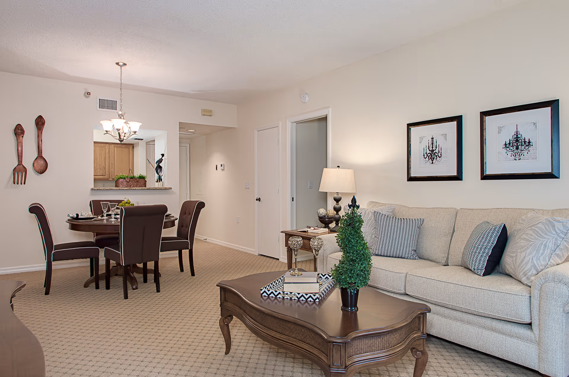 Bright open-plan living and dining area with a beige sofa, wooden coffee table, and a round dining table with chairs.