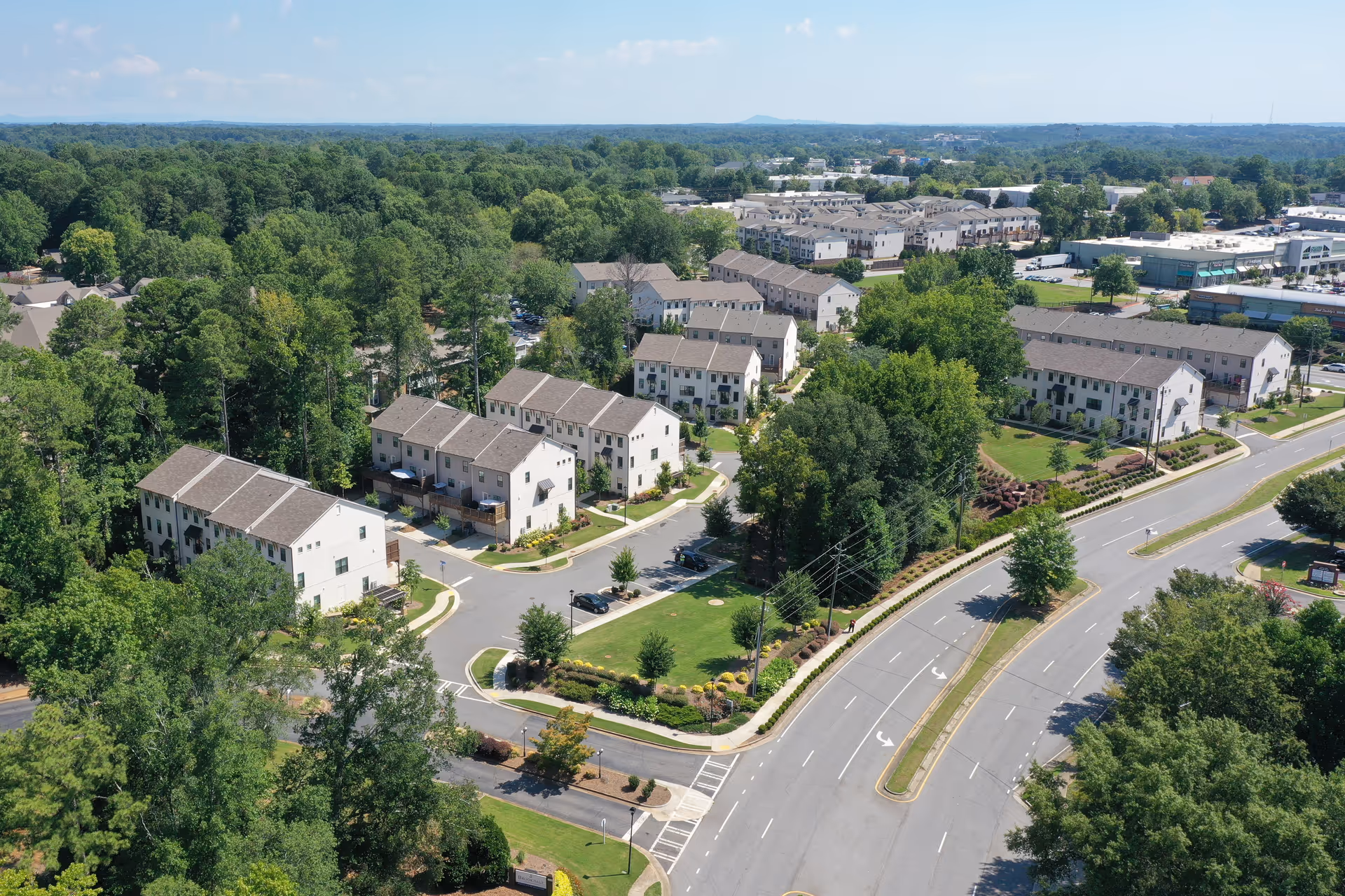 Aerial view of a suburban senior living community with multiple townhouse-style buildings, landscaped grounds, and curved roads.