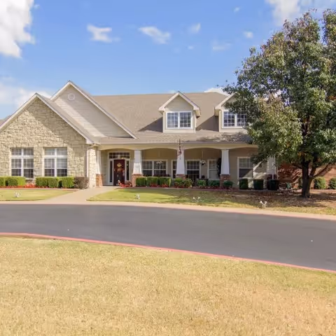 Exterior view of a single-story senior living facility with a landscaped front yard.