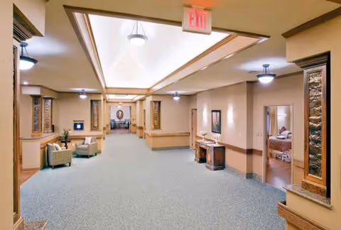 Long pastel hallway at The Maples Health and Rehabilitation with seating areas and pillars.