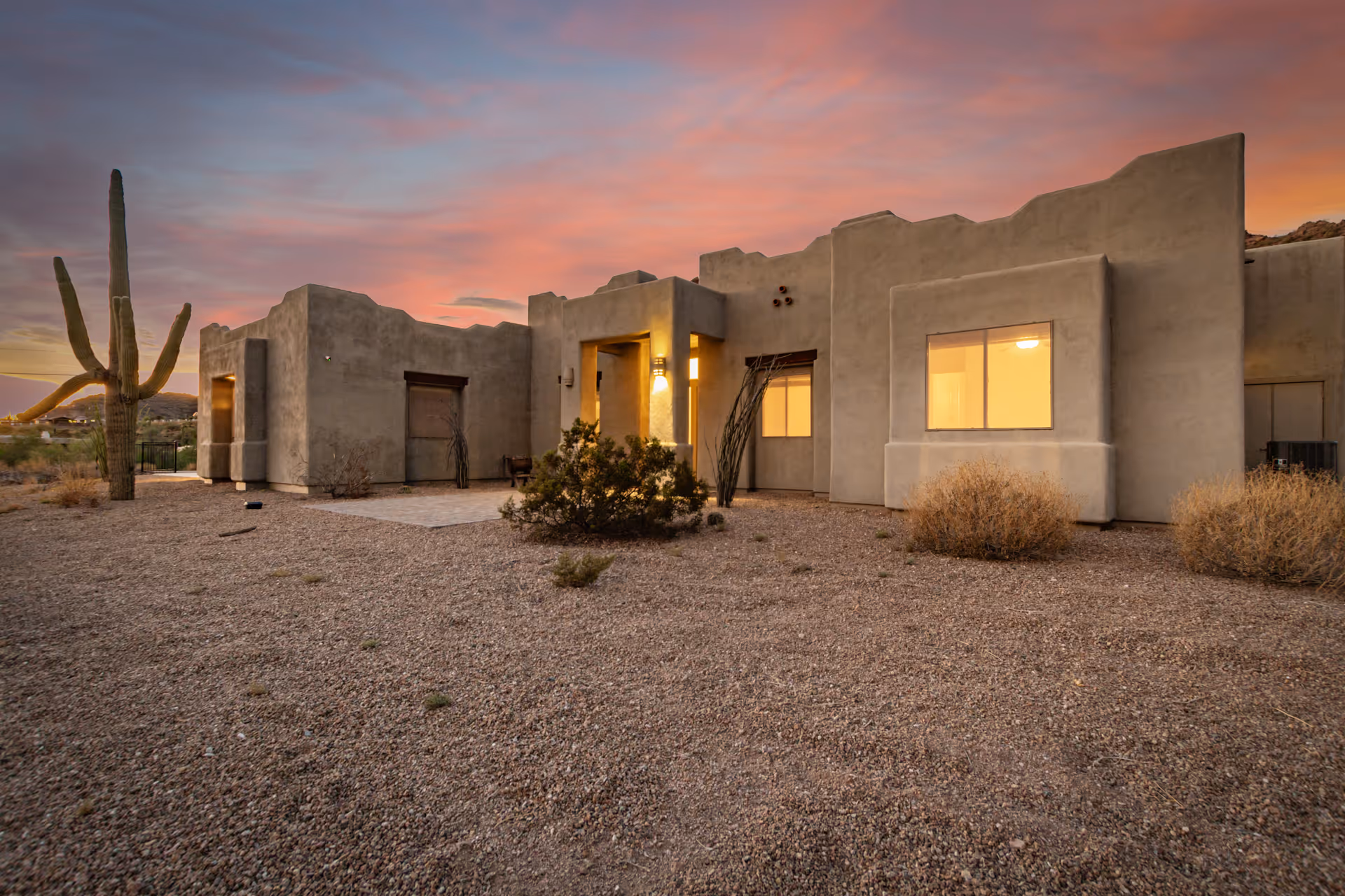 Exterior southwestern-style senior living facility with desert landscaping and a sunset sky.