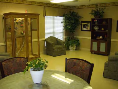 Interior lounge area featuring a round table, potted plant, and seating with a cabinet.