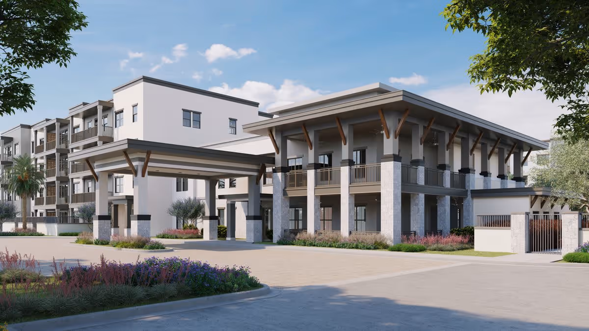 Exterior view of a modern multi-story senior living facility with a covered entrance, balconies, and landscaped surroundings under a blue sky with some clouds.