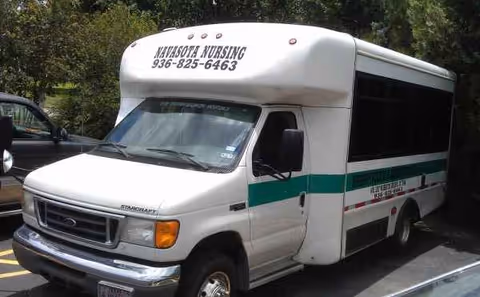 White shuttle bus labeled Navasota Nursing & Rehabilitation parked in a parking lot.
