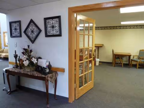 Interior hallway with a wooden French door, decorative wall art, and a floral console table.