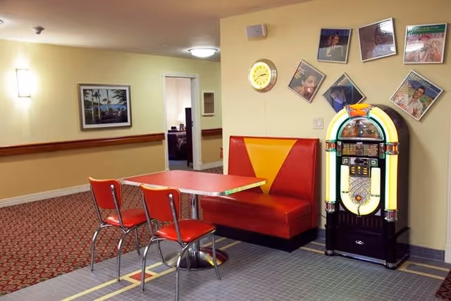 Retro diner-style booth and table with red chairs and a jukebox in an interior common area.