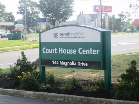 Green Court House Center sign along a street with landscaping and 144 Magnolia Drive