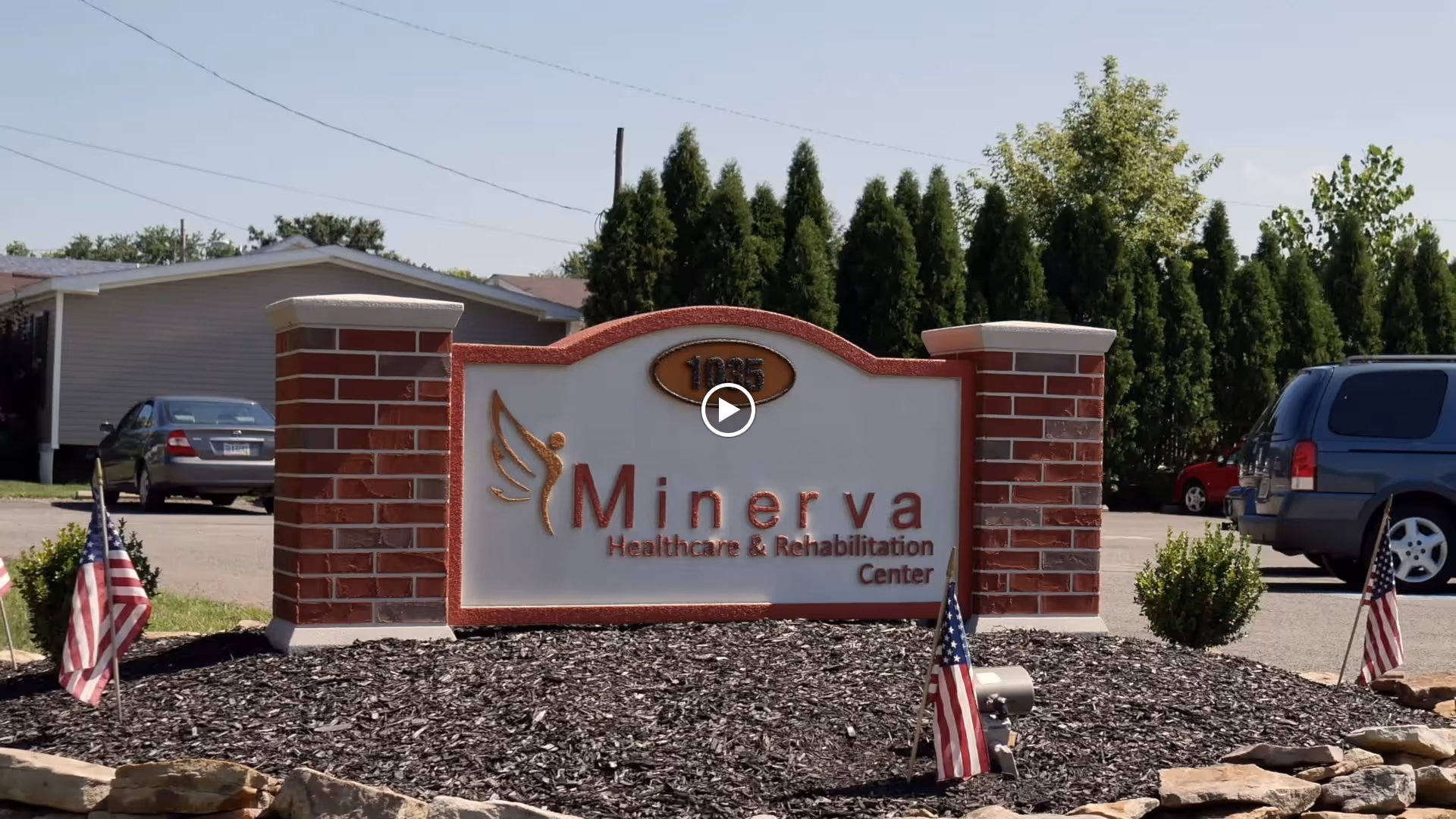 Sign of Minerva Healthcare and Rehabilitation Center with American flags in the foreground.