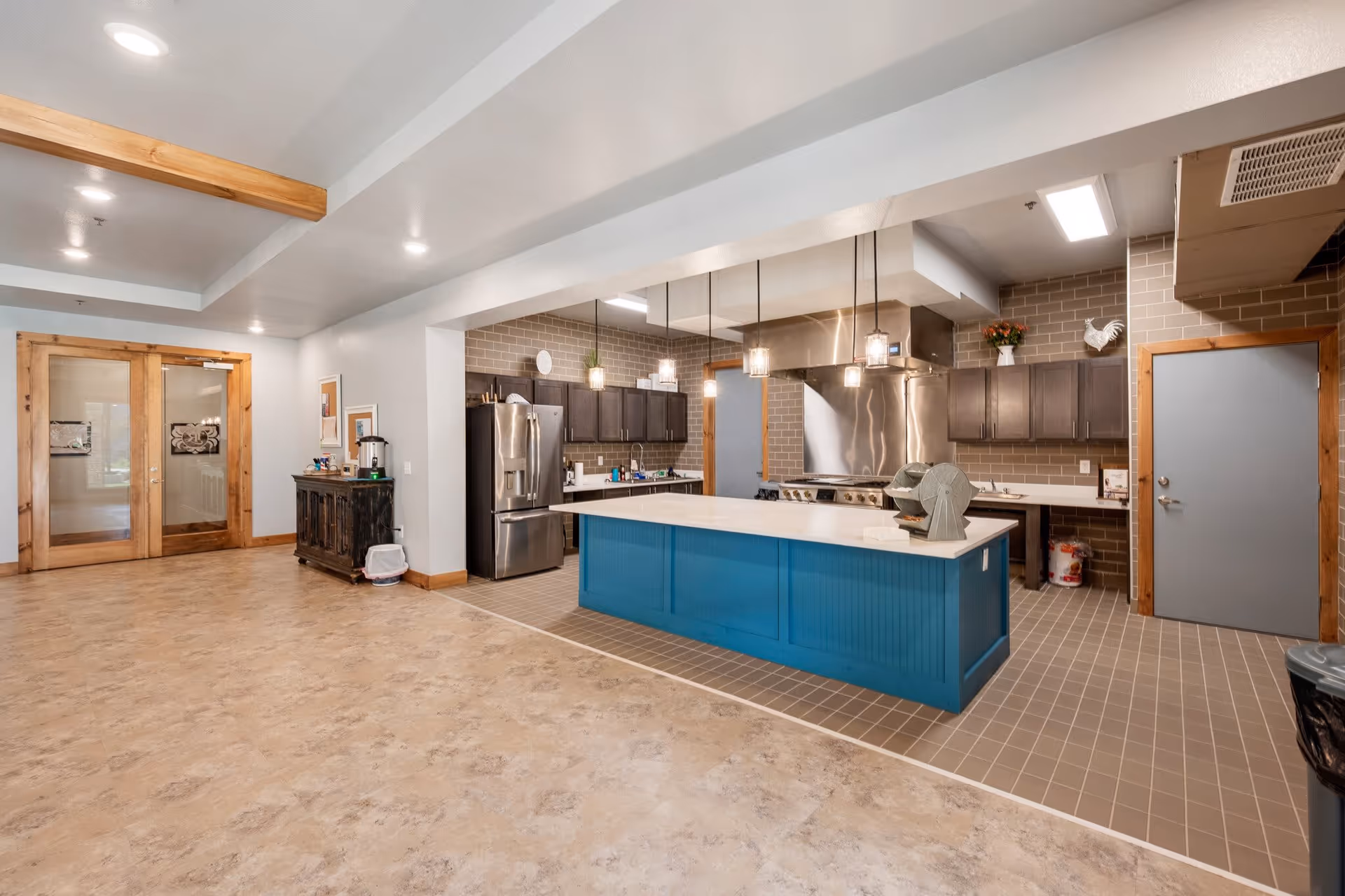 Large communal kitchen with a blue island, stainless steel appliances, and open floor space.
