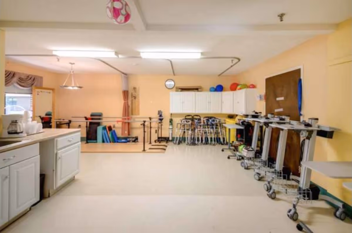 Interior rehab gym in a senior facility with exercise equipment and storage cabinets.