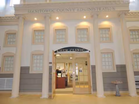 Front entrance of Manitowoc County Administration building with columns and glass doors.