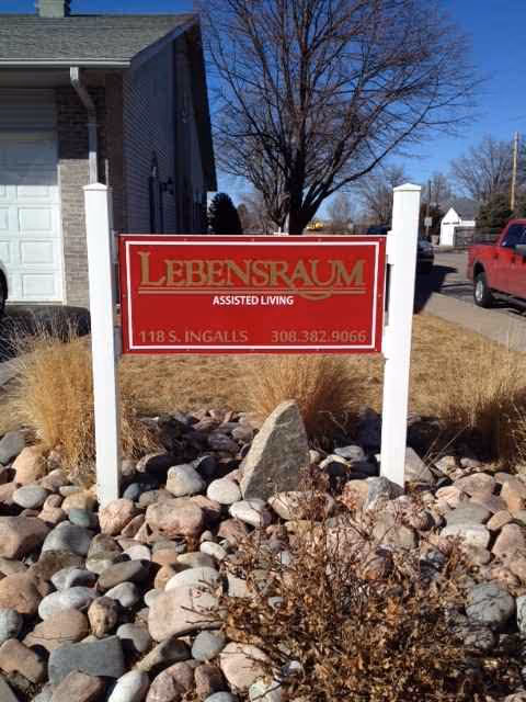 Red Lebensraum Assisted Living sign in rock landscaping with building exterior behind