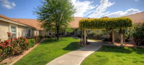 Front exterior of Brookdale East Arbor with lawn, trees, and walkway.